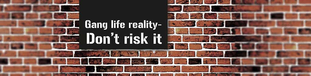 Brick wall background with sign 'Gang life reality - don't risk it'