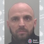 Bald man in his 30s with a dark beard. 