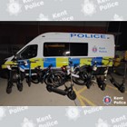 Seized bikes and e-scooters next to police van.
