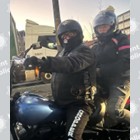 A man and woman on a motorcycle wearing dark clothing and helmets