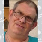 A white man in his 60s with shaven dark hair.