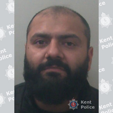 A balding man in his 40s with a dark full beard. 